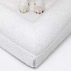 Patas de un perro sobre el tejido de la funda Bouclé Blanca Pethijos